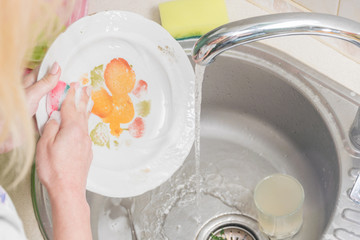Female hands wash the plates. Homework in the kitchen. Creation of cleanliness and order.