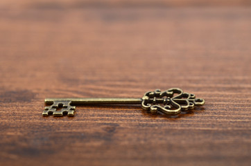 Old vintage key on a wooden background.