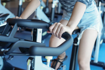 Close-up women working out in gym on the exercise bike,
