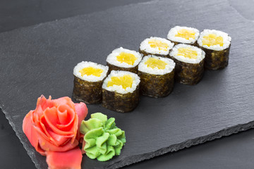 Japanese restaurant, sushi roll on black slate plate.