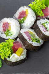 Japanese restaurant, sushi roll on black slate plate.
