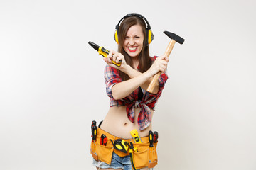 Strong fun young handyman woman in plaid top shirt, denim shorts, noise insulated headphones, kit...