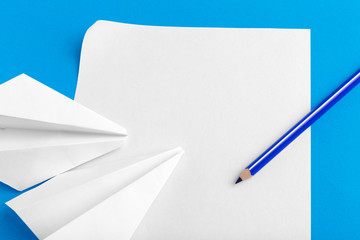 Flat lay of a paper plane on pastel blue color background