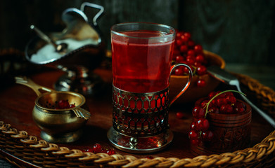 Still life in vintage style. Close up glass and decanter with red current tea or fruit-drink on...