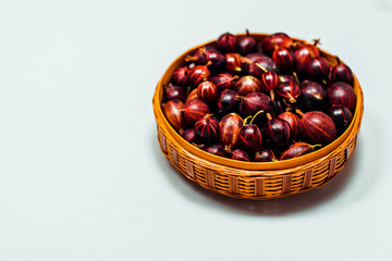 Close up little basket with red gooseberry on white background
