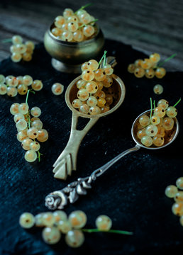 With white berries and bunches lay in vintage spoons and around black stoun stand. Vertical shot