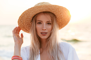Cute blonde woman wearing hat outdoors at the beach