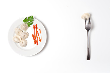 Traditional Russian dumplings, ravioli, dumplings on a white plate with red sauce and parsley.The fork is stuck in the dumpling. White background. Top view. Copy space