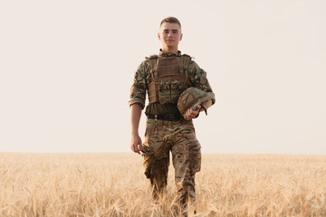 Soldier man standing against a field. Portrait of happy military soldier in boot camp. US Army...
