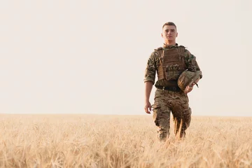 Poster Soldier man standing against a field. Portrait of happy military soldier in boot camp. US Army soldier in the Mission. war and emotional concept. © Misha