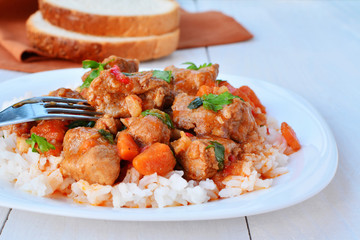 Pork stew with white rice in white plate over white wooden table