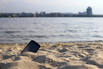 Phone lost on the beach in the sand.