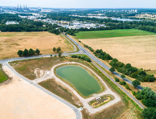 Aerial view of a rain retention basin at the edge of a new development, taken oblique