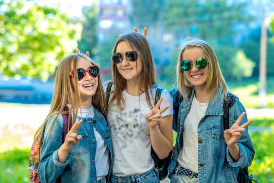 Three girls schoolgirl teenager, wearing jeans clothes and sunglasses. Happy smiling with gesture of hands showing Hello. Emotions of happiness and relaxation. The concept is best school friends.