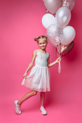 portrait of a little girl with balls, on a pink background in a photo Studio, close-up