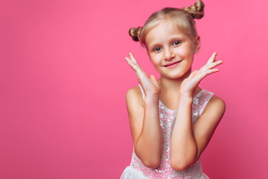 Portrait of a beautiful little girl, on a pink background, in a photo Studio, close-up