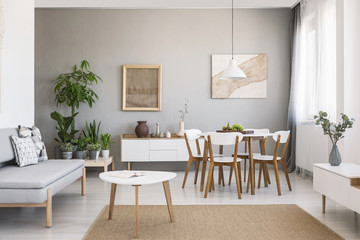 Real photo of a spacious dining and living room interior with wooden furniture and plants on a...