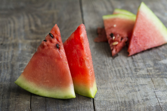 Several pieces of ripe watermelon on a wooden surface.