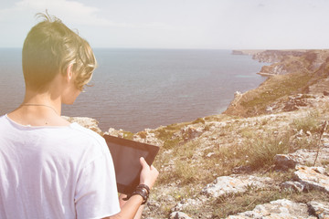 An attractive guy and a tablet. Sea and vacation. 