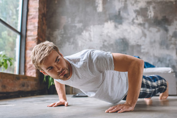 confident young man doing push ups during morning time at home