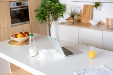 selective focus of laptop, coffee and fresh juice on table at kitchen