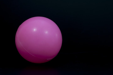 Object of plastic pink ball on black background.