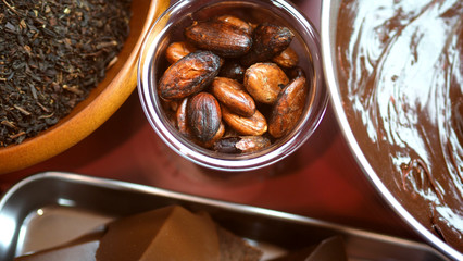 Close-up images of chocolate bar top view angle and cocoa seed with bowl of dark brown cream milk swirling by handmade for represent one of delicious sweet in the World