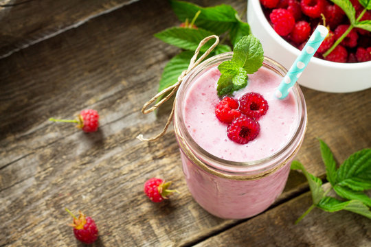 Raspberry milkshake or smoothie on a white wooden background. Healthy juicy vitamin drink diet or vegan food concept. Copy space.