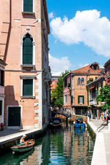 Fototapeta na wymiar Venice canals with gondolas on a sunny day with people walking by