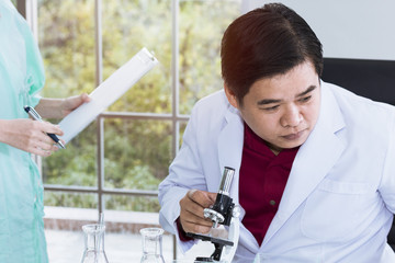Senior male scientist looking through a microscope in a laboratory. Man scientist researchers working.Copy space.