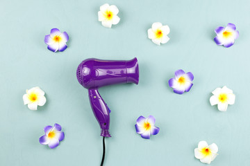Purple hair dryer with flowers on blue wooden background