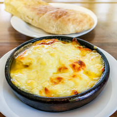 Fried suluguni cheese. Georgian national dish in a clay plate.