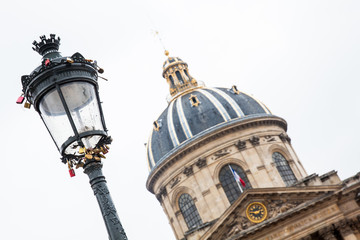 Fototapeta na wymiar Street lamp with love locks next to the Institute of France