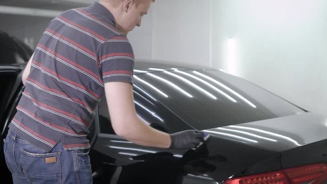 Hand putting spray while taking care of car in the garage