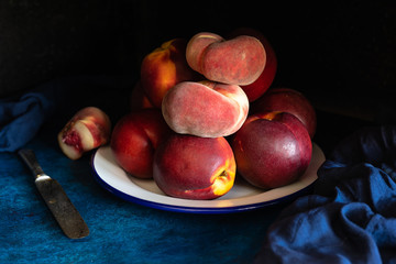 peaches in a metal dish. One of them is cut to show the inside