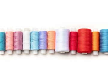 An overhead photo of a row of thread spools, shot from above on a white background with copy space