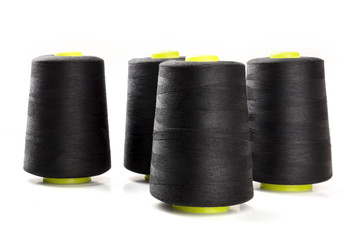 A side view of large black thread spools on a white background with copy space