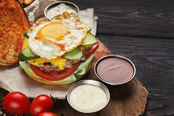 Hamburger with bacon and egg on wooden platter