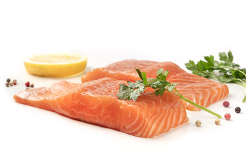 Slices of salmon with lemon, parsley, and pepper, on a white background with copy space