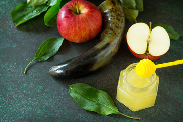 Background Rosh hashanah (Jewish New Year). Traditional holiday symbols - shofar, honey and apple on a stone or slate background. Copy space.