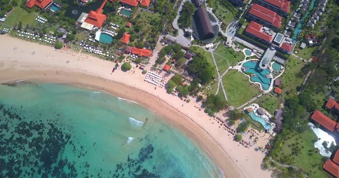 Flying above luxury secluded  beachfront resort with ocean  view on Bali island with sandy coastline at Nusa Dua beach line,Indonesia