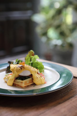 Breakfast food egg benedict , poached egg with yellow sauce with waffle and smoked salmon on wood background