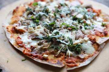 Pizza with  ham tomatoes mozzarella cheese and basil. Delicious italian pizza on wooden pizza board