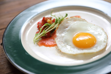 Zucchini fritters with egg and smoked salmon on wood background vinage style