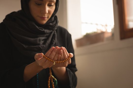 Muslim woman with prayer beads praying at home