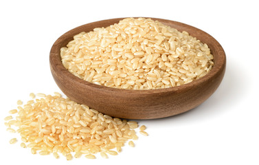 raw brown rice in the wooden plate, isolated on the white background