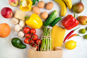 Healthy food background. Healthy food in paper bag vegetables, fruits, pasta, eggs, cheese and mushrooms on white. Shopping food supermarket concept. Top view