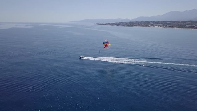 Aerial shot tracking a parasailing boat in Crete, Greece
