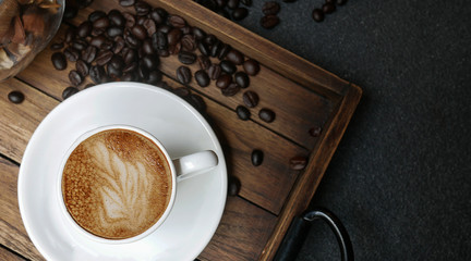 Coffee in white cup on woodden plate with coffee bean,top view with copyspace for text.