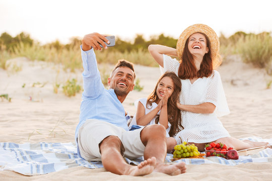 Laughing family having fun together outdoors make selfie by mobile phone.